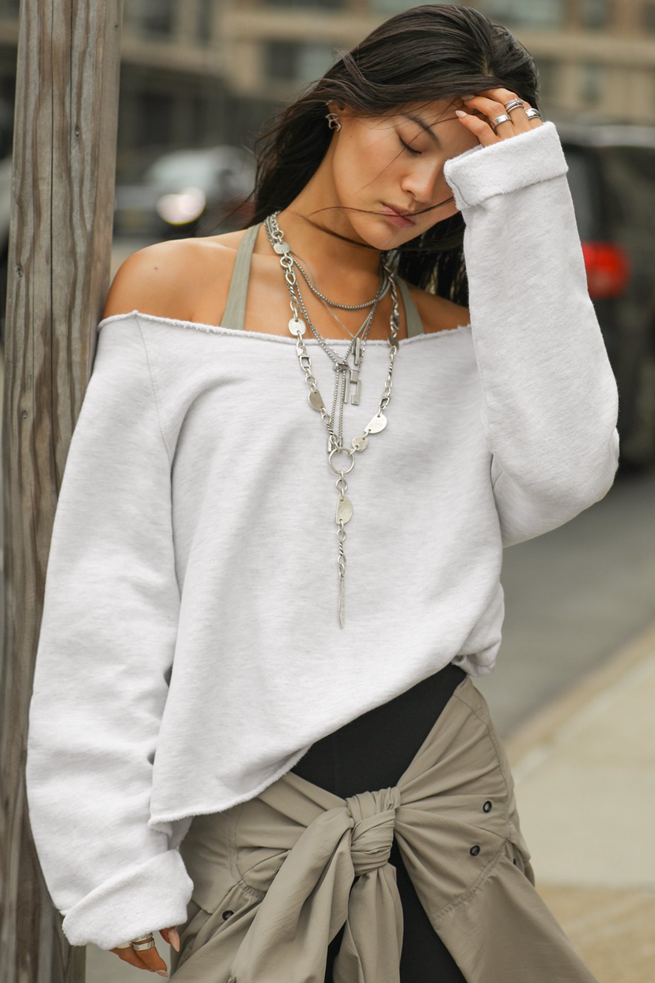 Front view of model posing outside in the oversized pearl grey french terry Slouchy Pullover Sweatshirt with a wide, off-the-shoulder neckline and a JOAH BROWN logo patch on the right sleeve