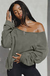 Front view of model posing in the oversized washed sage french terry Slouchy Pullover Sweatshirt with a wide, off-the-shoulder neckline and a JOAH BROWN logo patch on the right sleeve