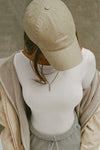 Bird's eye view of model wearing the six-panel desert Official Cap with a curved brim and an embroidered upside down Joah Brown logo on the front