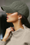 Side view of model wearing the six-panel washed green Official Cap with a curved brim and an embroidered upside down Joah Brown logo on the front