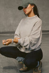 Side view of model squatting and posing in the comfortable sand french terry Turtleneck Sweatshirt pullover with a side split in the collar and a slightly oversized fit