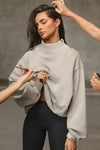 Front view of model posing in the comfortable sand french terry Turtleneck Sweatshirt pullover with a side split in the collar and a slightly oversized fit