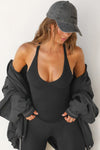 Front view of model posing in the fitted stretchy black flexrib V Neck Racerback Tank with a deep v neckline and thin straps