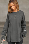 Front view of model posing in the oversized washed black cotton Vintage Panel Long Sleeve with a crew neckline, intricate panel details and eyelets on the chest and sleeve which you can thread jewelry through