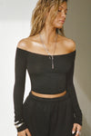 Front view of model posing in the fitted, slightly cropped black modal Bare Shoulder Long Sleeve top with a straight, off-the-shoulder neckline