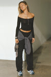 Full body front view of model posing in the fitted, slightly cropped black modal Bare Shoulder Long Sleeve top with a straight, off-the-shoulder neckline