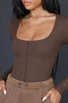 Close up front view of model posing in the fitted brown rib Classic Scoop Long Sleeve top with a scoop neckline and vertical stitch detail down the center front bodice
