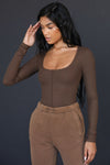 Front view of model posing in the fitted brown rib Classic Scoop Long Sleeve top with a scoop neckline and vertical stitch detail down the center front bodice