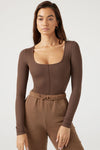 Front view of model posing in the fitted brown rib Classic Scoop Long Sleeve top with a scoop neckline and vertical stitch detail down the center front bodice